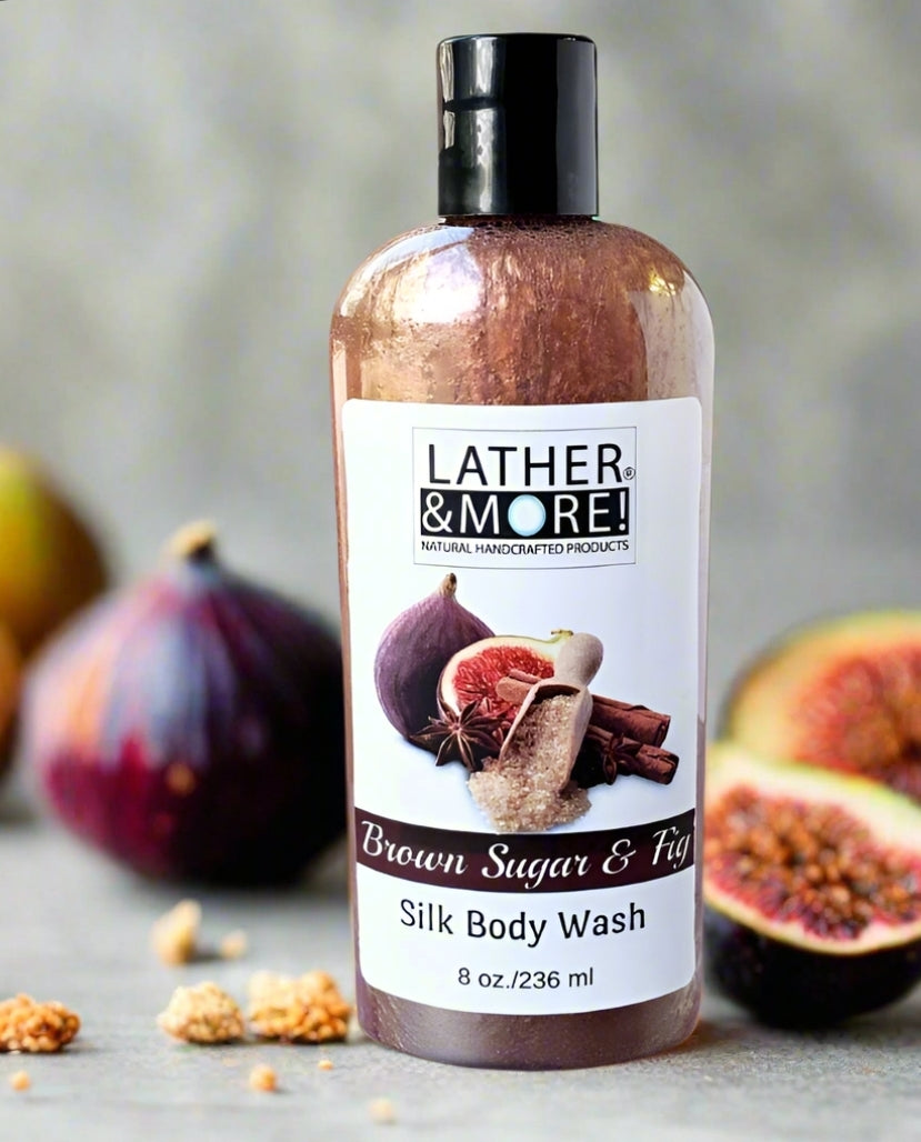 Brown Sugar & Fig Silk Body Wash - Brown colored liquid soap in a clear bottle with black top, surrounded by fresh figs. Label shows brand logo and product name with images of figs and brown sugar on front label.