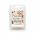 A packaged soy wax melt in a clear plastic clamshell package. The label reads 'Cocoa Butter CASHMERE' with a warm cream and blush-toned photo of folded fabric and an open book.