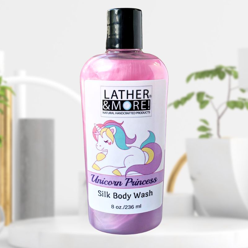 A bottle of Unicorn Princess Silk Body Wash with branding logo and product name with images of a unicorn on the front label. Product is pink and purple liquid in a clear bottle with a black top on a white background. placed against a bathroom backdrop.