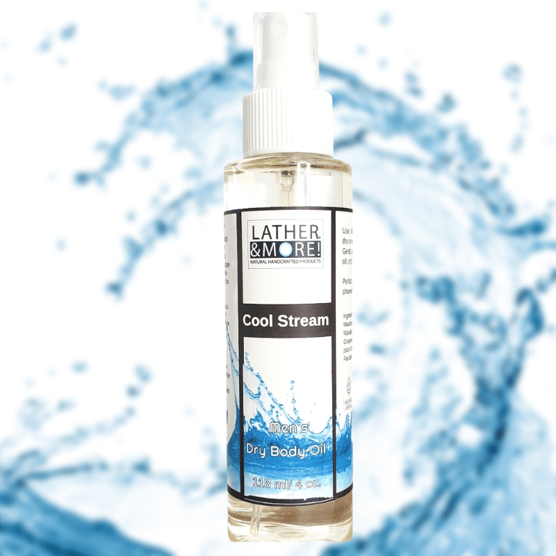 A bottle of Cool Stream Dry Body Oil by Lather and More, with a white spray nozzle, labeled with the product name and a blue water splash background.